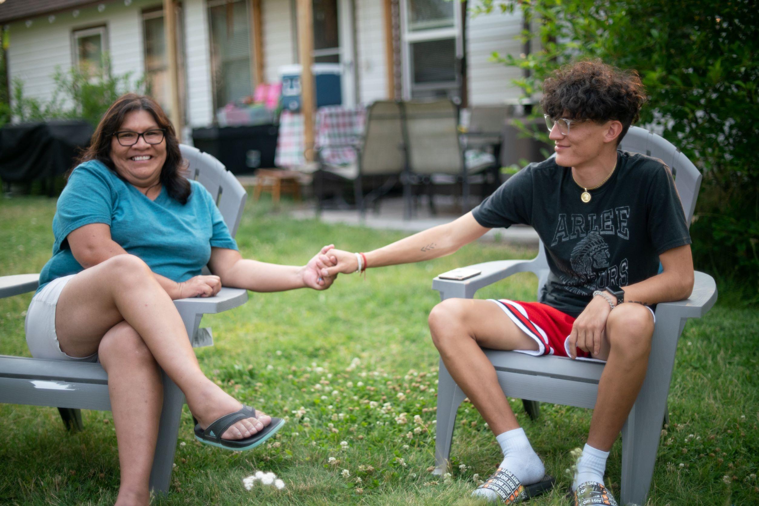 Raelena Whitesell and her son Greg hold hands, smiling.