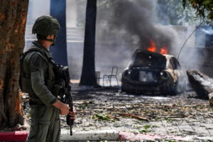 A soldier looks at a burning car at the impact site of a rocket that was fired towards Israel from Lebanon, amid ongoing c...